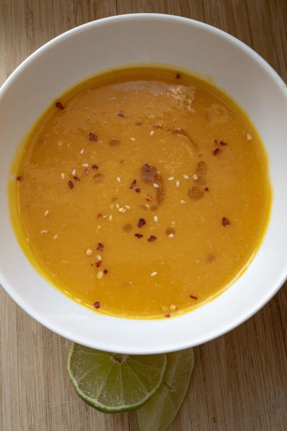 Creamy squash Soup in a white bowl on a wooden board.