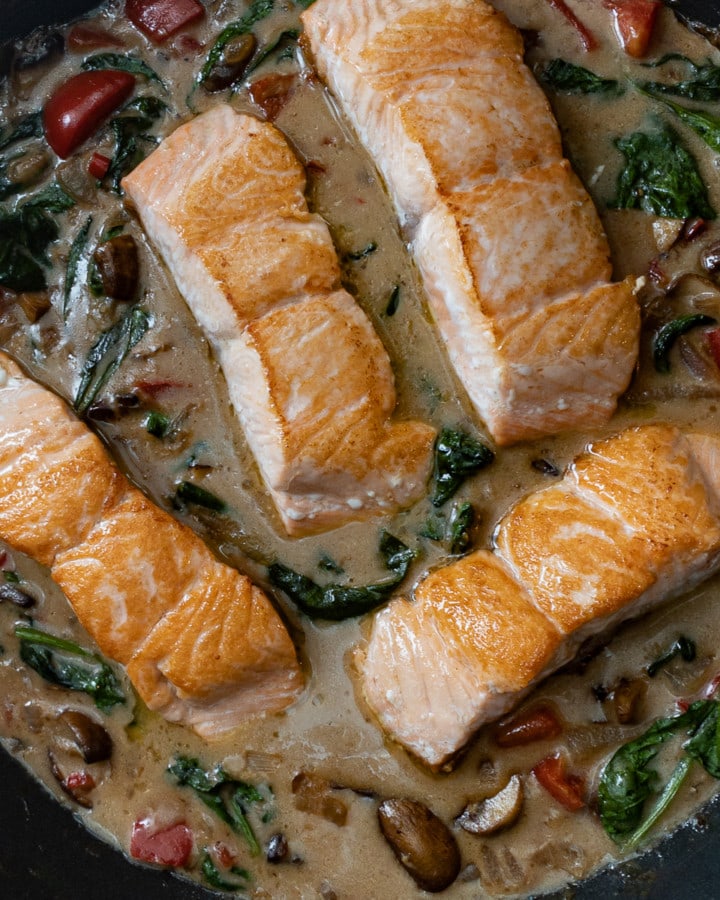 pan seared salmon fillets in pan on coconut sauce