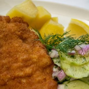Crispy pork Schnitzel with cucumber salad and potatoes on the side