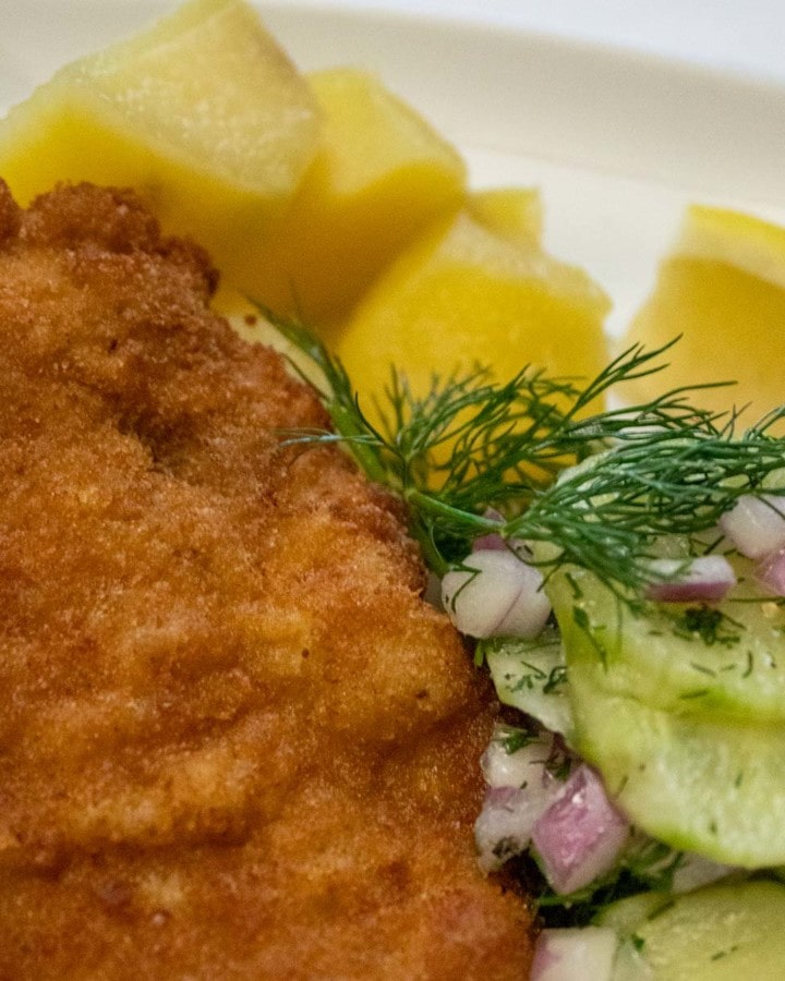 Crispy pork Schnitzel with cucumber salad and potatoes on the side