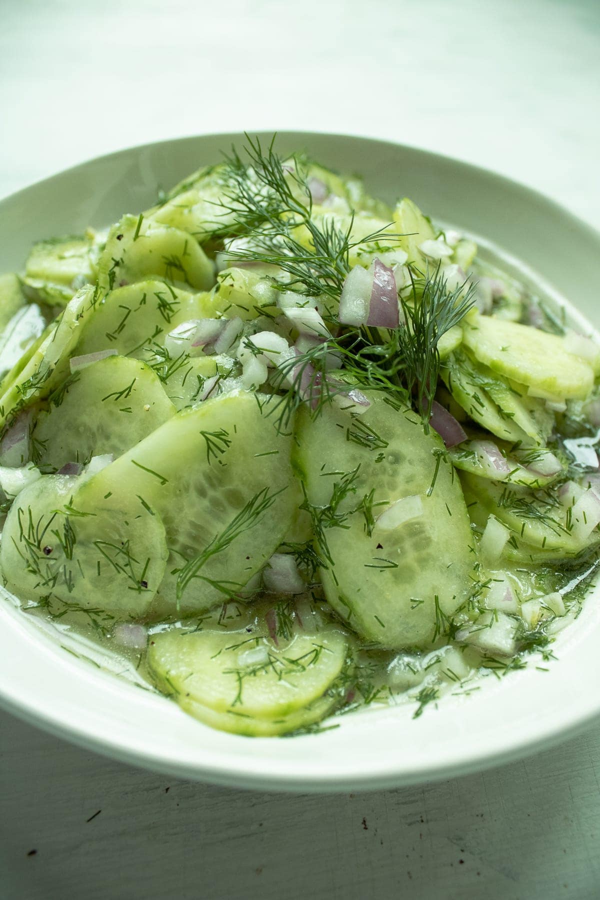 Cucumber salad with dill and red onions in a white bowl