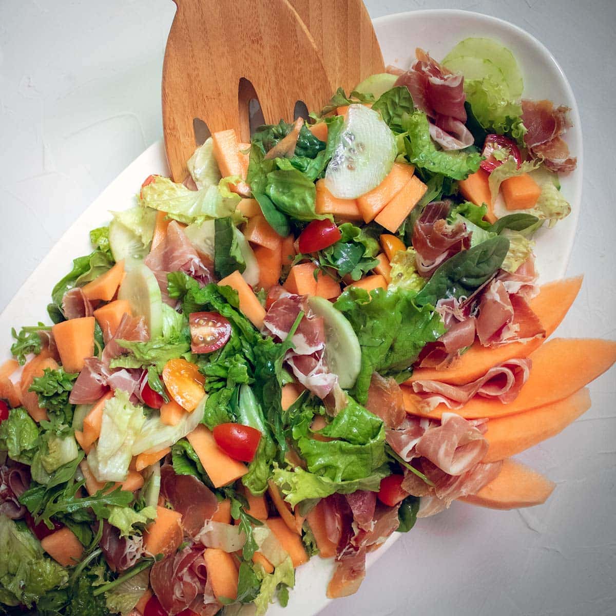 top view on melon and prosciutto salad on oval plate