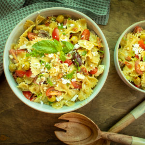 two bowls of pasta salad on a wooden table