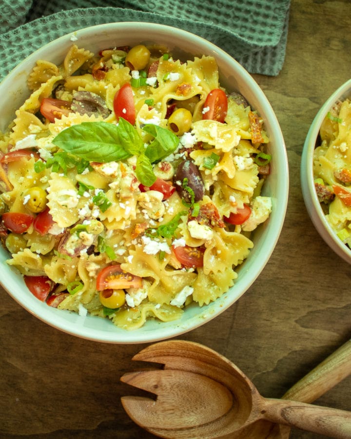 two bowls of pasta salad on a wooden table