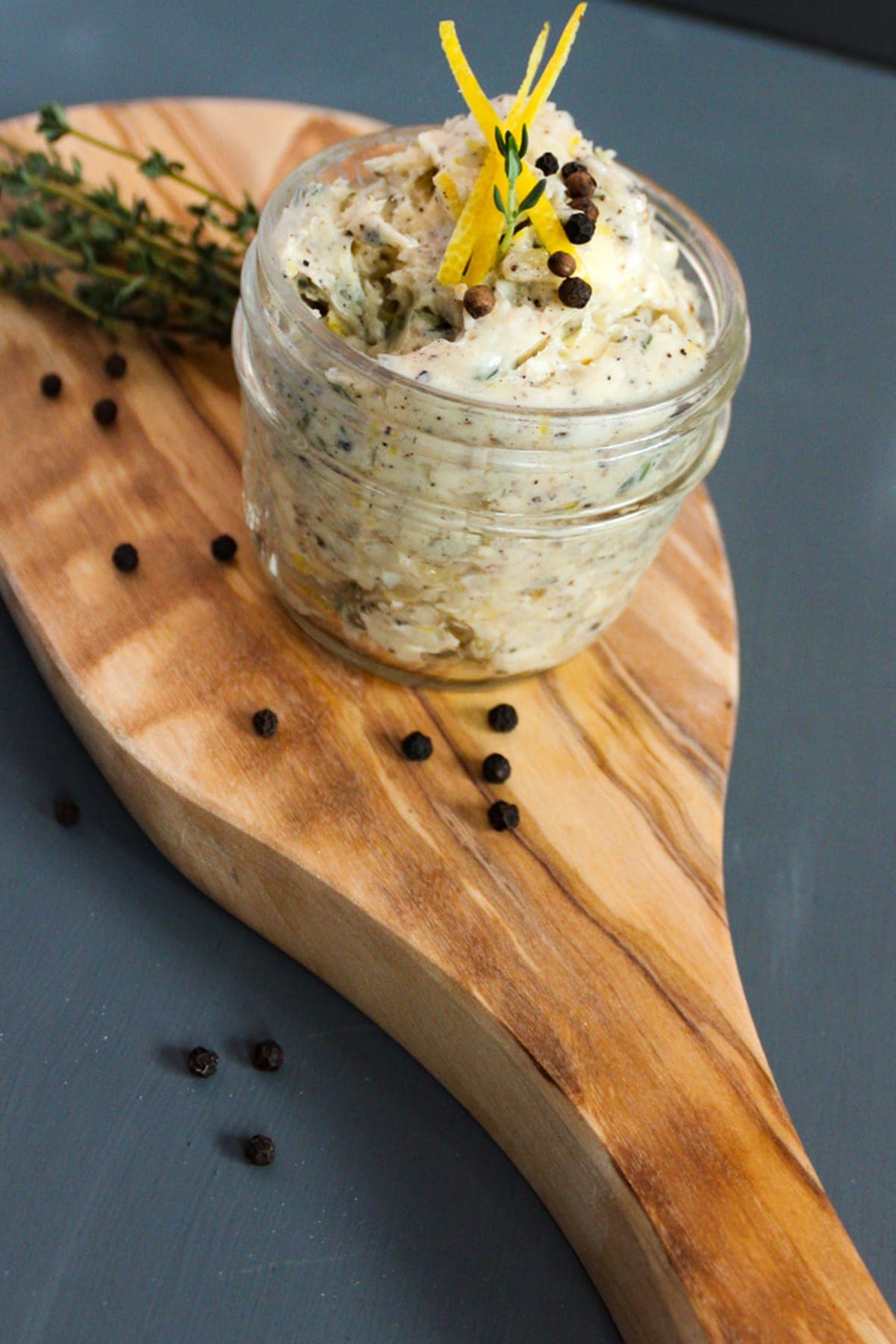 Garlic butter in a jar on a wooden board, garnished with Thyme and lemon zest