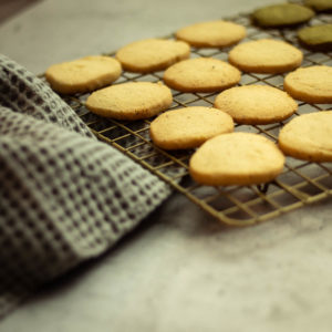 Shortbread cookies on a cooling rack and a kitchen towel in the left corner
