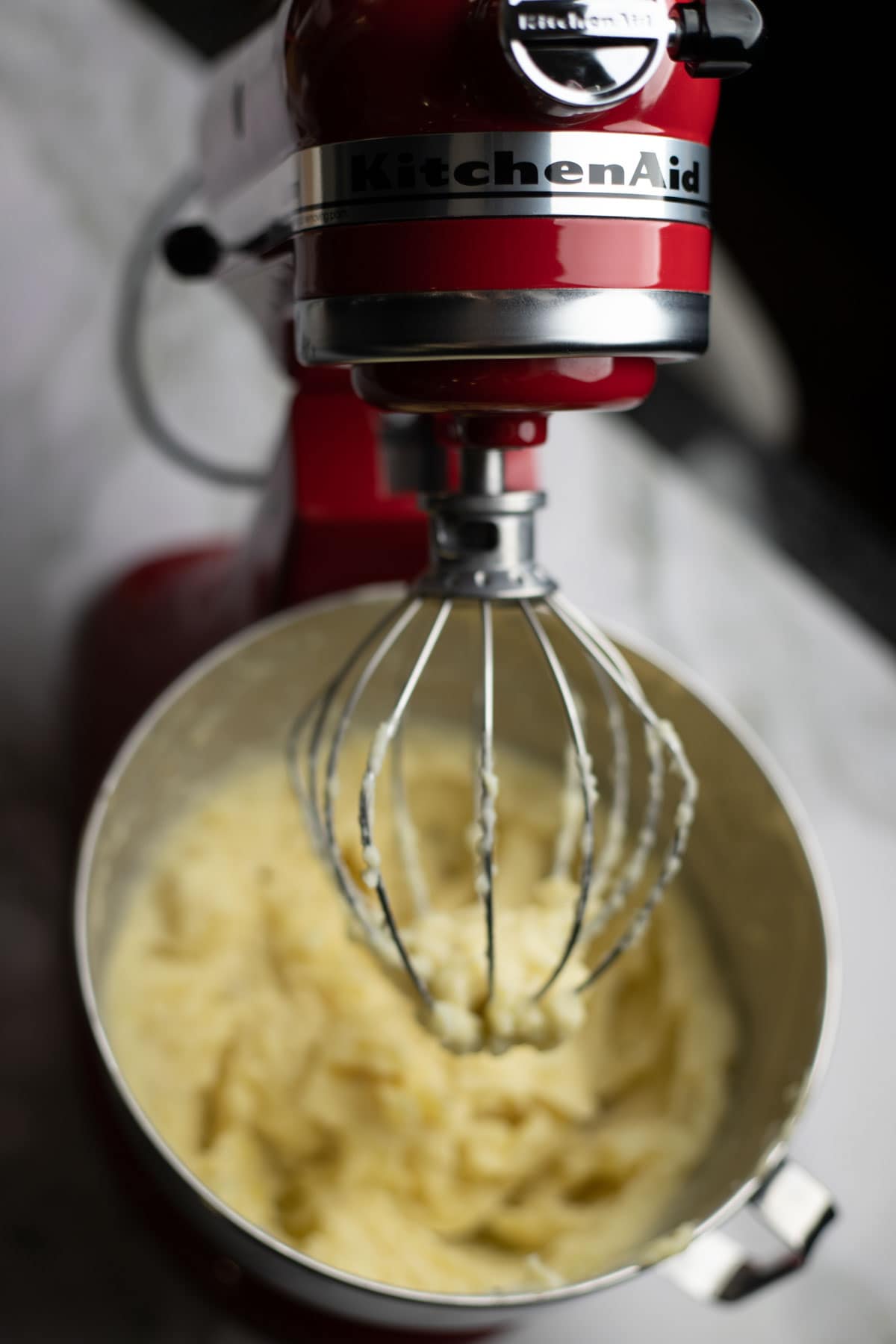 Red Kitchenaid stand mixer with mashed potatoes in bowl.