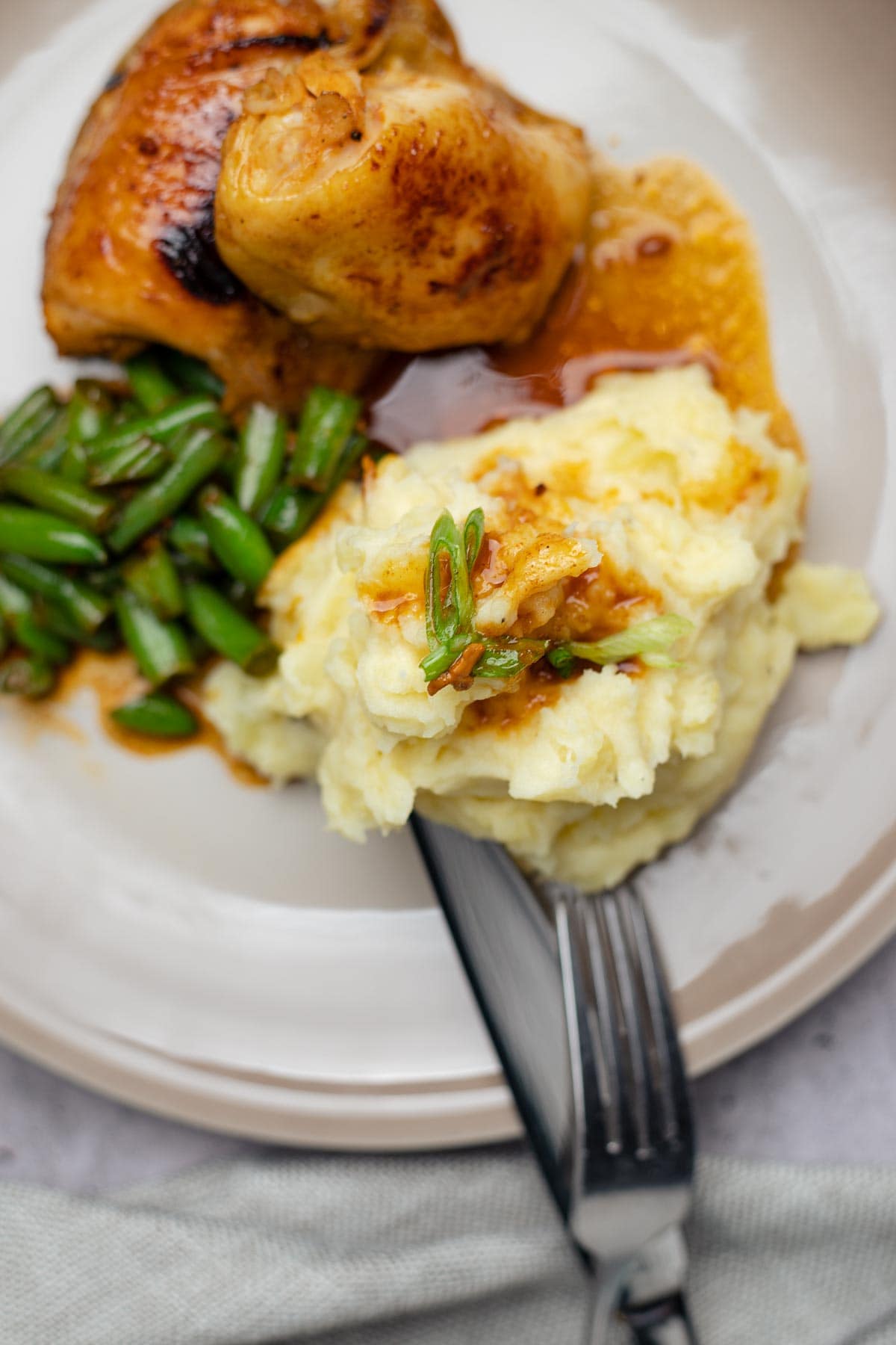Mashed potatoes made in kitchen aid mixer on a plate with sous-vide chicken thighs and green beans.