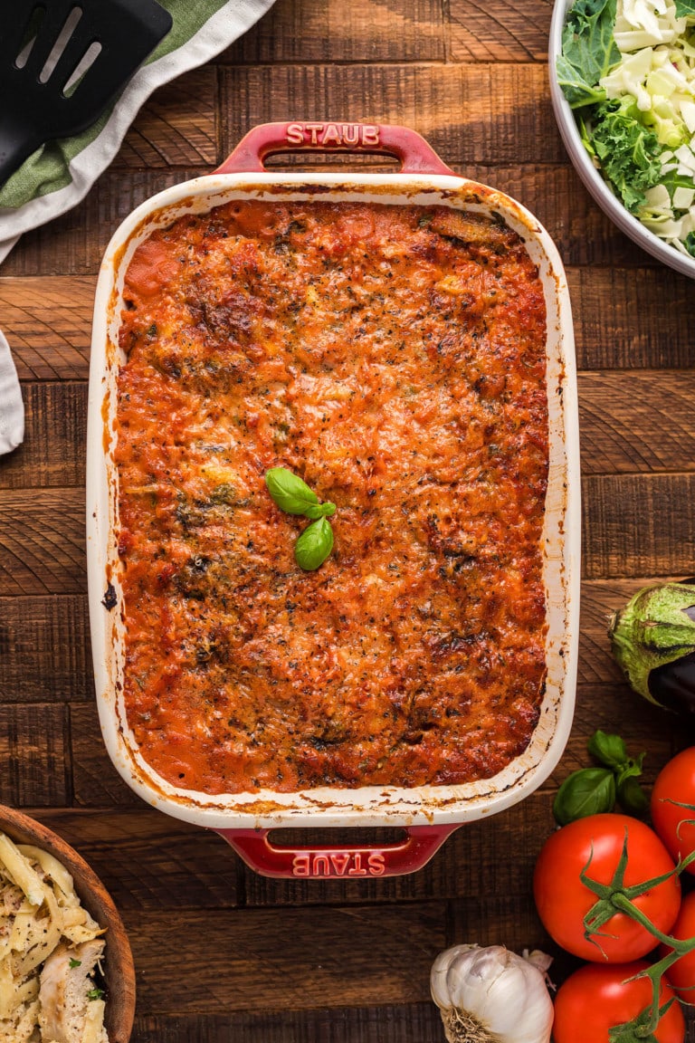 Casserole with eggplant Parmigiana on wooden surface.