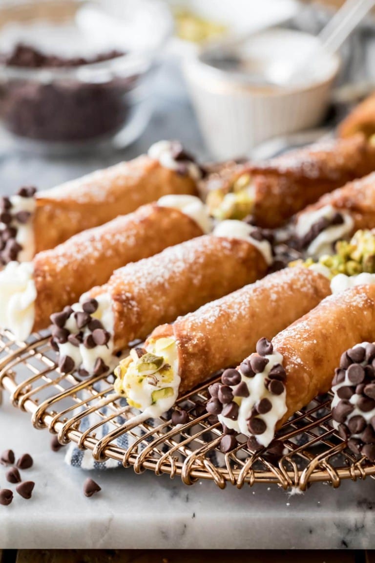 Cannolli with creamy stuffing , garnished with chocolate chips and pistachios.