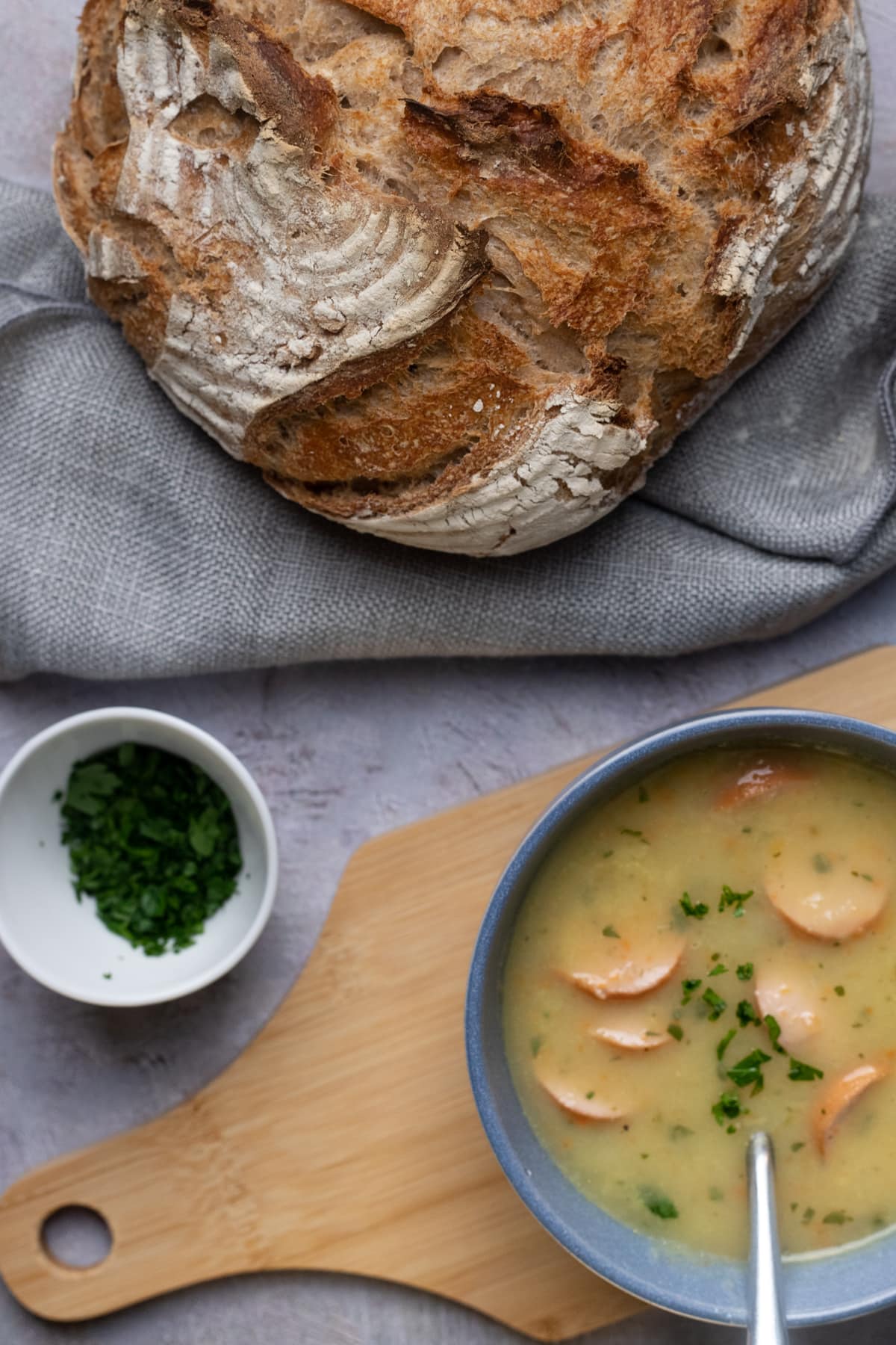 bowl with potato soup and a loaf of bread next ti it.